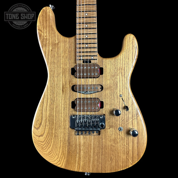 Electric guitar with a wooden finish on a black background, featuring the Tone Shop logo.