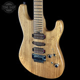 Wooden electric guitar with a clear finish on a black background, featuring the Tone Shop logo.