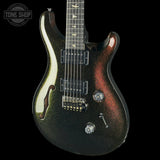 A double-cutaway electric guitar with a black and red glitter finish, featuring a cream-colored pickguard and chrome hardware, shown against a solid black background.