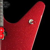 Close-up of a red glitter electric guitar body with a silver toggle switch and part of the neck visible against a black background.