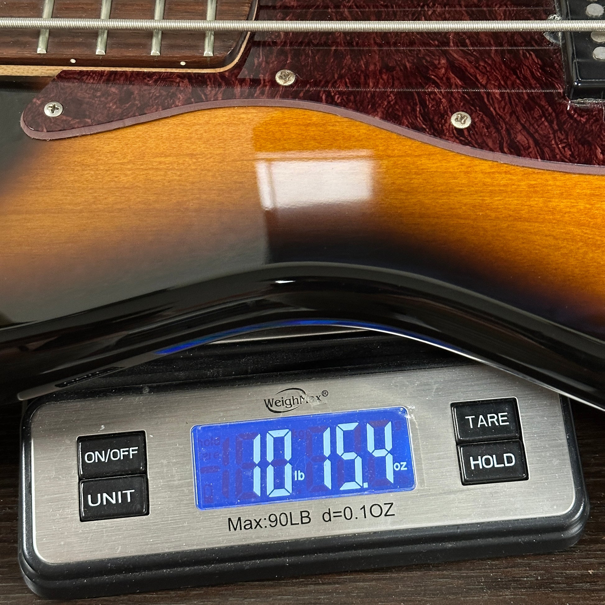 Used Ken Smith Proto 5 String Sunburst on scale displaying weight.