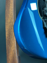Close-up of a blue car fender with a wooden surface below