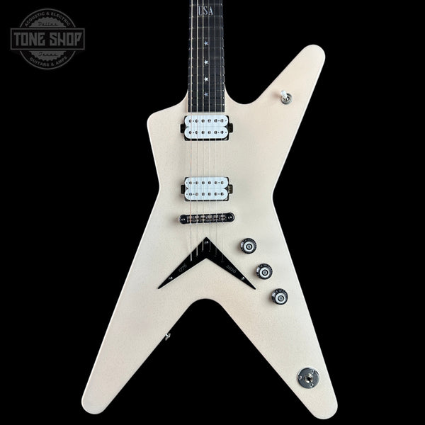 An electric guitar with a distinctive angular, V-shaped body in a light natural wood finish, featuring black hardware and pickguard, set against a solid black background.