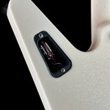 Close-up of a guitar body showing the side profile, a black hardware pocket with visible internal wiring, and a black background.