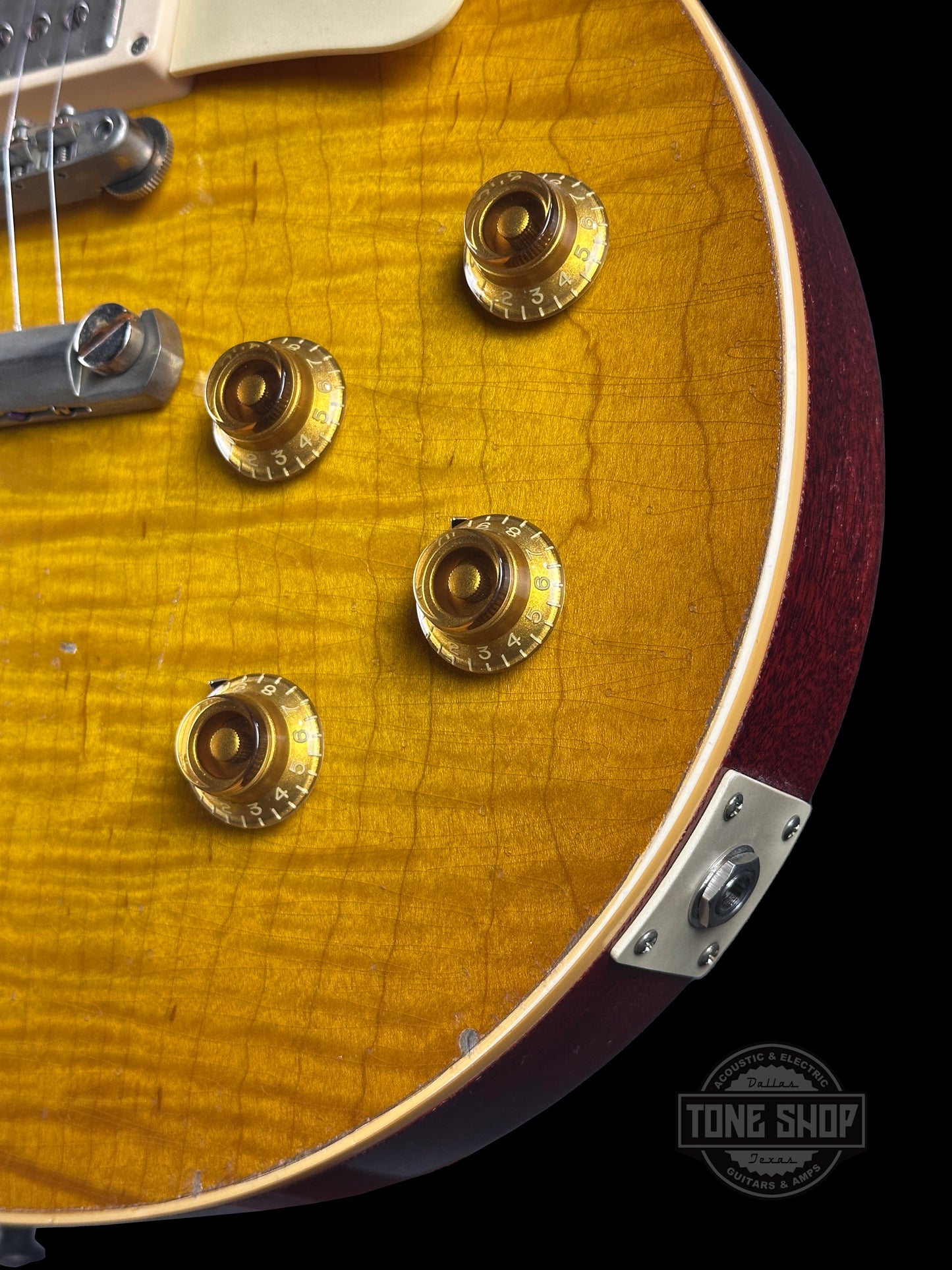Close-up of a guitar's body with visible hardware, brand logo in the corner.