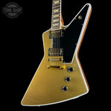 Gold electric guitar with a black pickguard on a white background, featuring 'Tone Shop' branding.