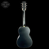 A dark acoustic guitar shown from the back against a solid black background, with a Tone Shop watermark in the upper left corner.