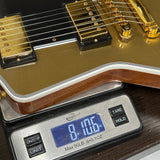 Gold electric guitar on a digital scale displaying weight