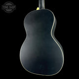 The back of a black acoustic guitar with a white edge trim, shown against a solid black background. A Tone Shop watermark is visible in the top-left corner.