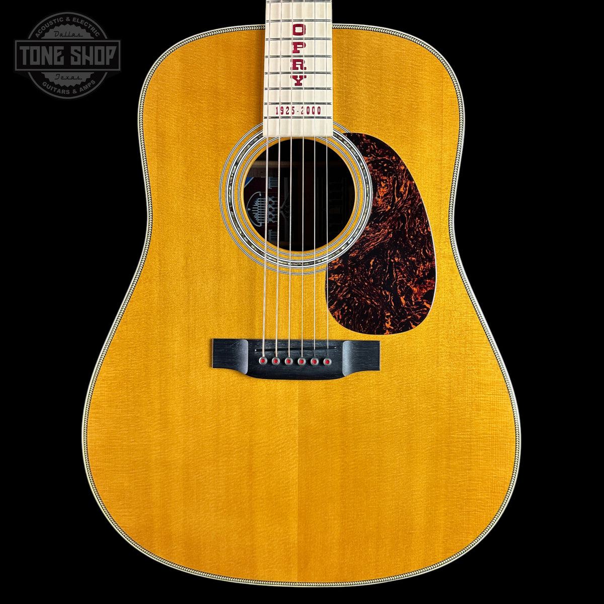 An acoustic guitar with a natural wood finish, featuring the brand name 'OSCY' and year '1935' printed on the neck, set against a solid black background.