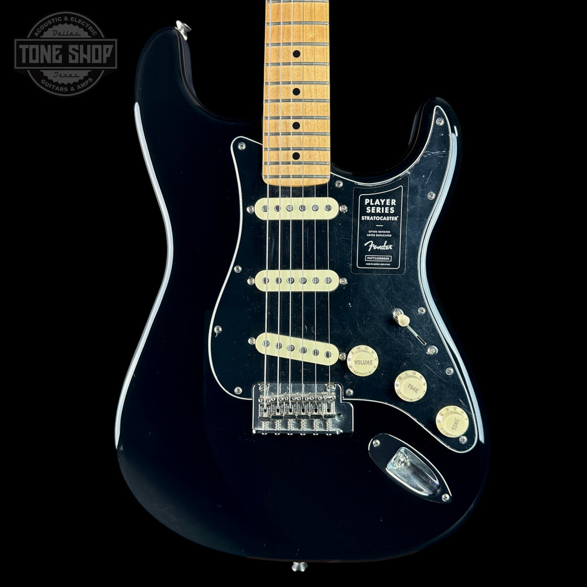 A black Fender Stratocaster electric guitar with a maple neck, cream humbucker pickups, and a black pickguard, shown against a solid black background with a Tone Shop watermark in the top left corner.