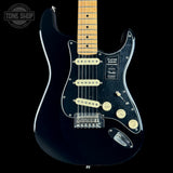 A black Fender Stratocaster electric guitar with a maple neck, cream humbucker pickups, and a black pickguard, shown against a solid black background with a Tone Shop watermark in the top left corner.