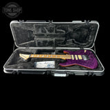 Purple electric guitar in a clear case with 'Tone Shop' logo.