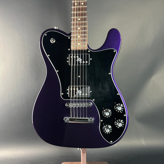 Electric guitar with a glossy purple finish on a gray background