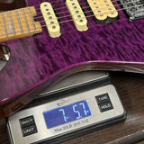 Purple electric guitar on a digital scale displaying weight