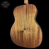 Close-up of the back of an acoustic guitar showing a rich wood grain finish on a solid black background, with a Tone Shop watermark in the top left corner.