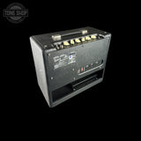 A black Fender Jazz Bass head amplifier shown from the rear, featuring cream-colored control knobs, a metal handle, and a vented grille on the back panel, set against a solid black background.