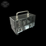A black metal electronic amplifier or speaker driver with a silver handle, shown from a three-quarters angle against a solid black background. A 'TONE SHOP' watermark is visible in the top-left corner.