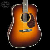 Acoustic guitar with a sunburst finish on a black background, featuring the Tone Shop logo.