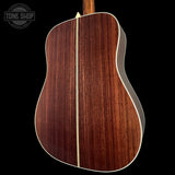 Close-up of a wooden acoustic guitar with a visible brand logo in the corner.
