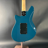 Blue electric guitar on a stand against a gray background