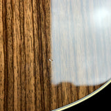 Close-up detail of a glossy wooden surface with prominent dark brown wood grain and a light reflective section, showing part of a curved edge with a thin white line.