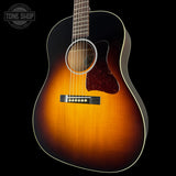 A classic acoustic guitar with a sunburst finish, featuring a dark black outer edge fading to a warm amber-orange center, set against a solid black background.