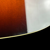 Close-up detail of a curved guitar body showing the sunburst finish, transitioning from dark brown to amber and a light gray edge, with a black lower section and a thin gold-toned binding line.