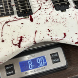 Digital scale displaying weight next to a guitar with red splatter design