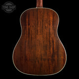 The back of an acoustic guitar with a rich, dark brown wood finish and a white binding edge, shown against a solid black background with a Tone Shop watermark in the top left corner.