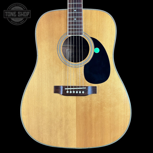 Acoustic guitar with a visible brand logo on a black background