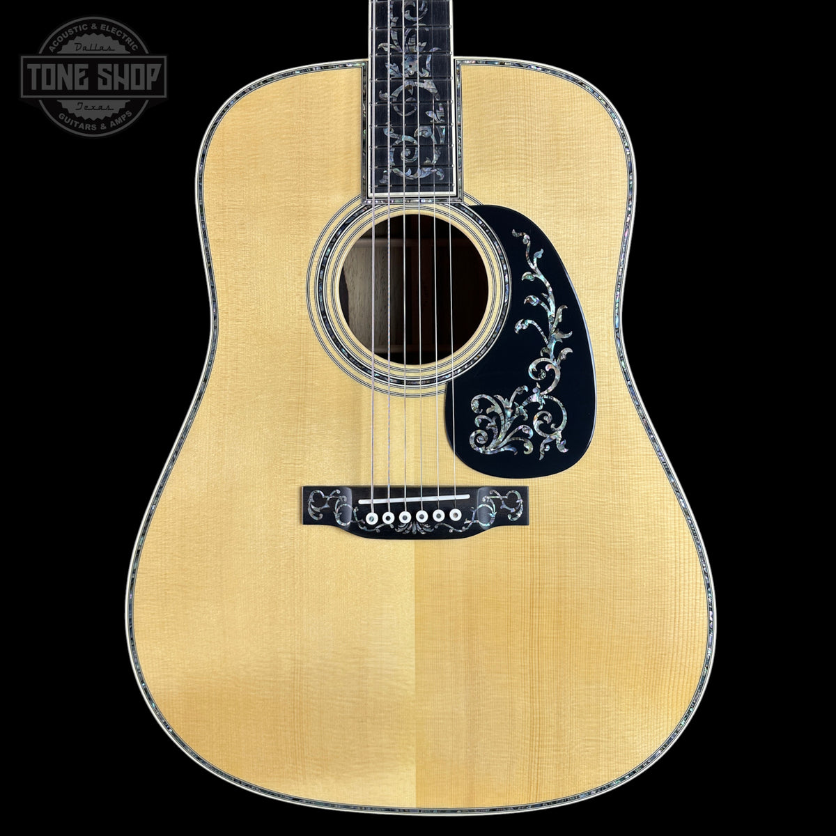 Acoustic guitar with decorative inlay on a black background, featuring the Tone Shop logo.