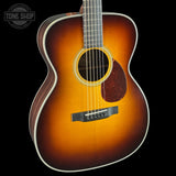 Acoustic guitar with a sunburst finish on a black background, featuring the Tone Shop logo.