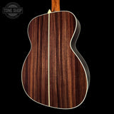 Back view of a wooden acoustic guitar with a visible brand logo in the corner.