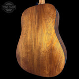 Close-up of a wooden acoustic guitar on a black background with 'Tone Shop' logo.