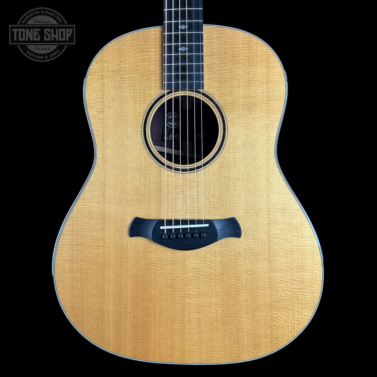 Acoustic guitar with a visible brand logo on a black background