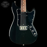 Black electric guitar with a clear coat on a black background, featuring the Tone Shop logo.
