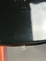 Close-up of a black surface with white residue and a metal button.