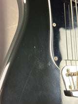 Close-up of a black guitar body with visible wear
