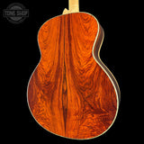 Close-up of a wooden acoustic guitar back with 'Tone Shop' logo.