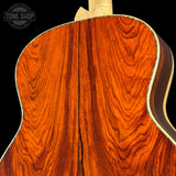 Close-up of a wooden acoustic guitar with a visible brand logo in the corner.