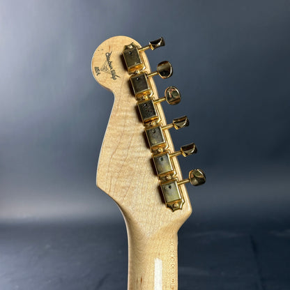 Guitar headstock with tuning pegs on a dark gray background