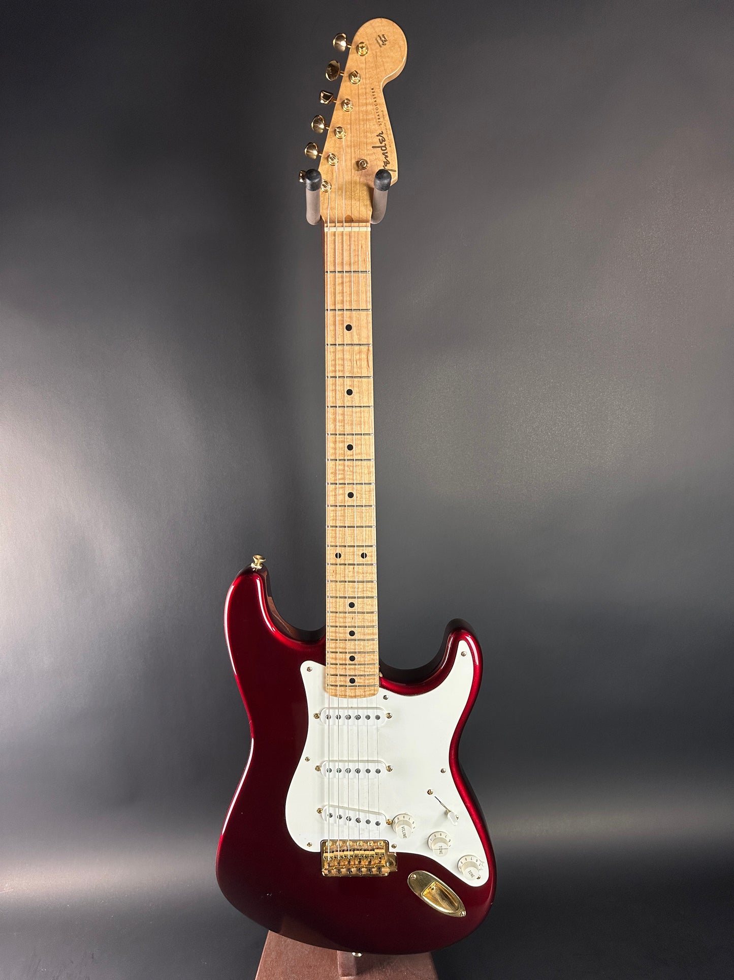 Electric guitar with a red body and white pickguard on a dark gray background