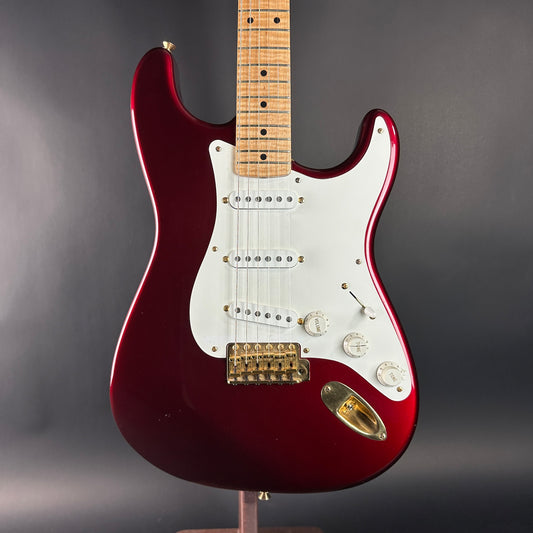 Red electric guitar with a white pickguard on a gray background