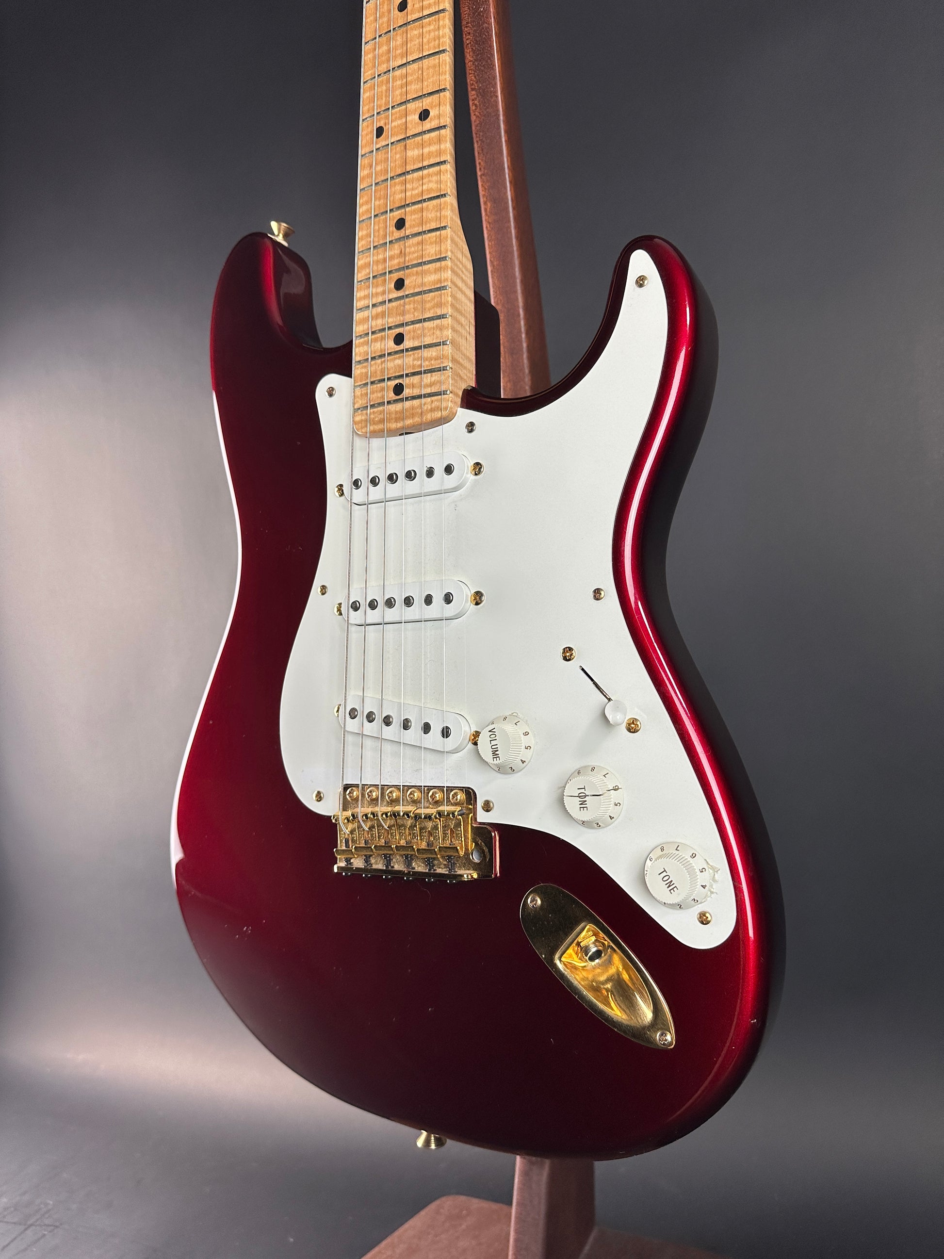 Red electric guitar with a white pickguard on a dark background