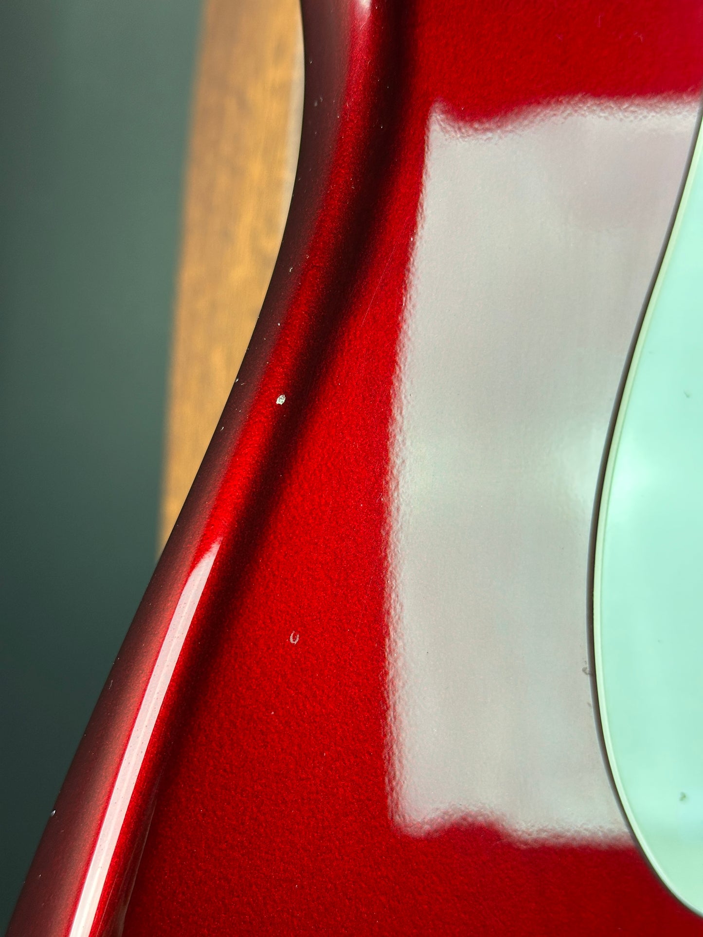 Close-up of a red guitar with a light green pickguard