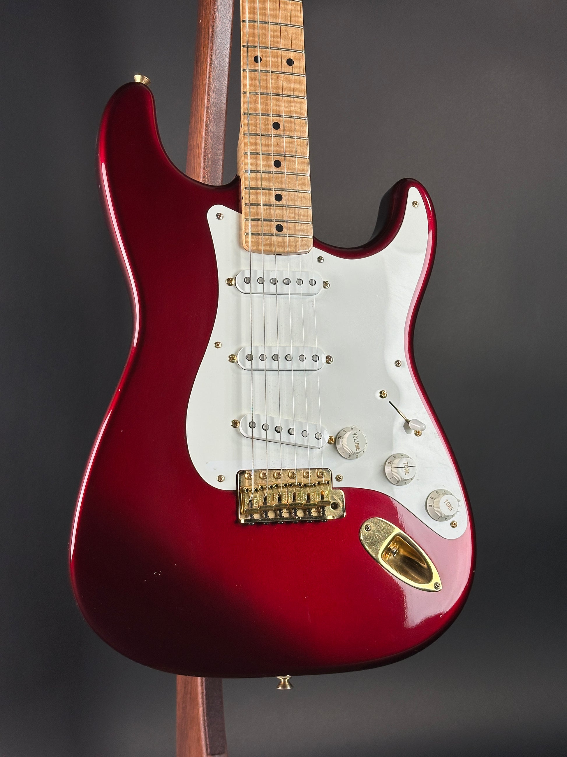 Red electric guitar with a white pickguard on a dark background