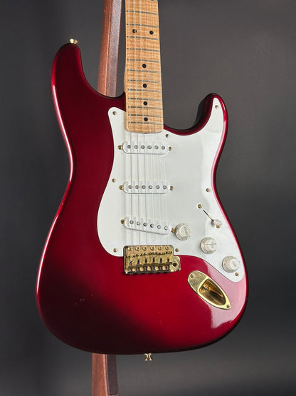 Red electric guitar with a white pickguard on a dark background