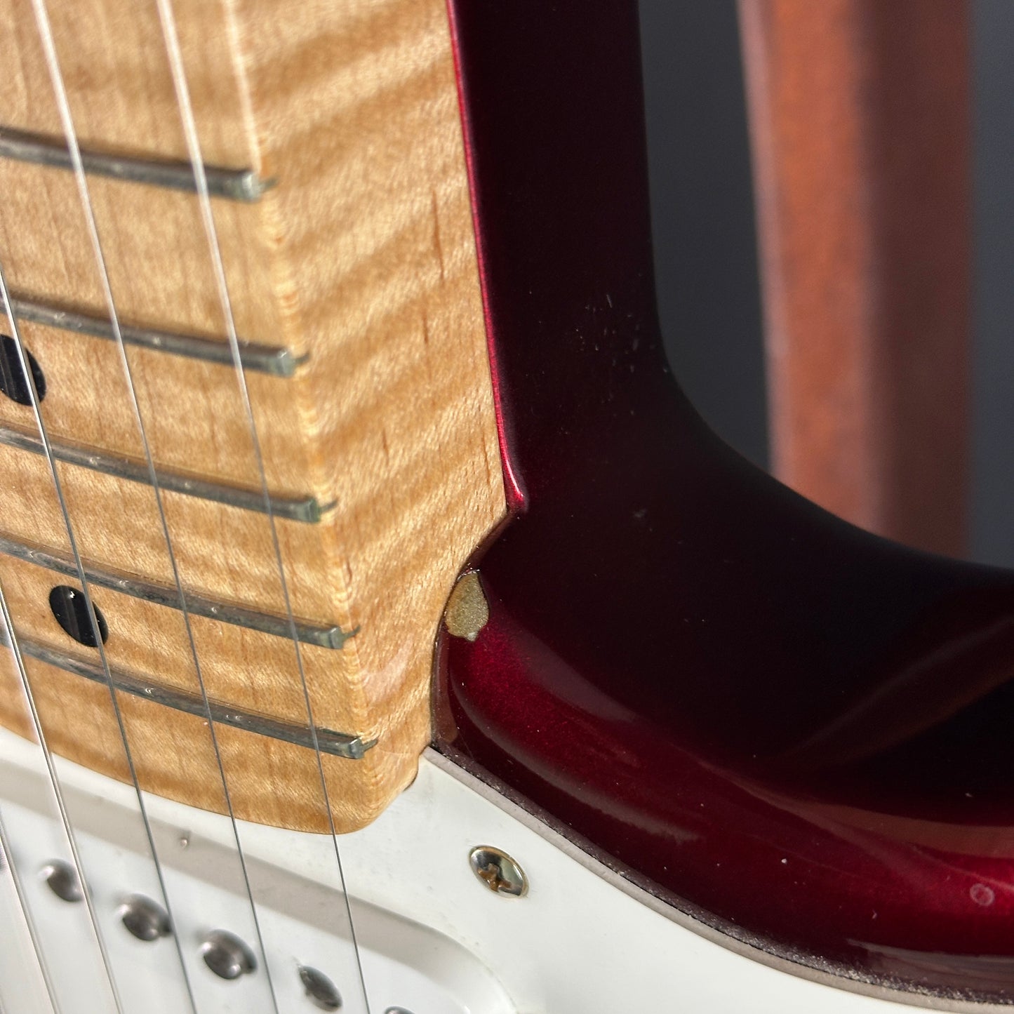 Close-up of a guitar's neck and headstock with a dark red finish.