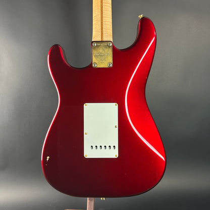 Red electric guitar with a white pickguard on a gray background